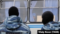 Russia - Migrant worker looks out of a police vehicle, OMON